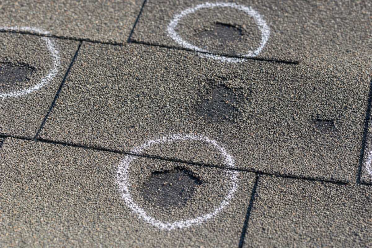 Hail damage on asphalt shingles in Lewisville, TX with impact bruises marked in chalk for the insurance adjuster